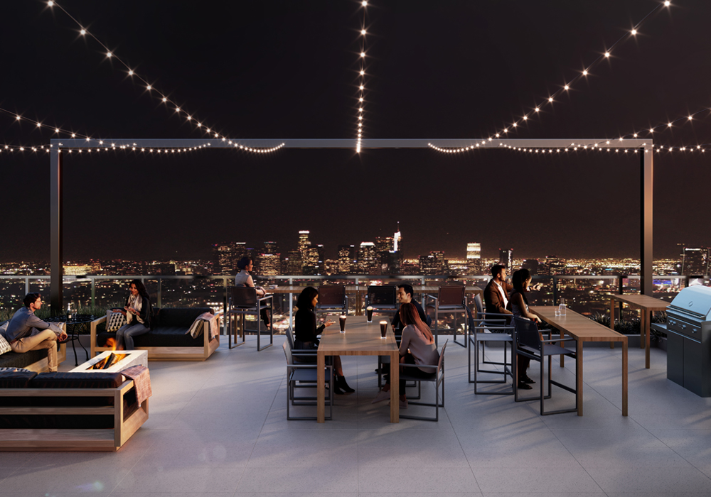 Rooftop deck with outdoor dining seating and BBQs with view of downtown Los Angeles skyline.